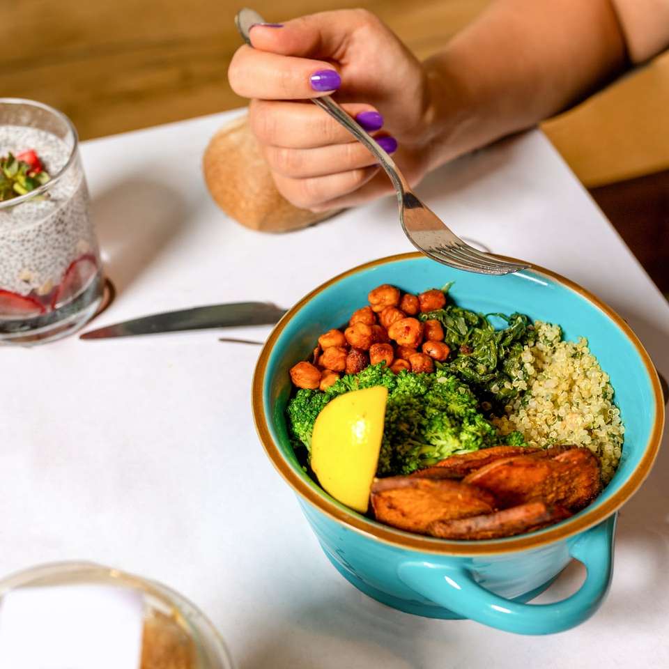 pessoa segurando uma colher com comida em uma tigela de cerâmica azul puzzle online