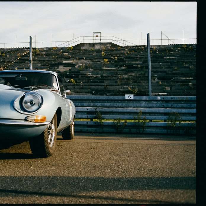 Porsche 911 branco estacionado ao lado de uma parede de tijolos puzzle online