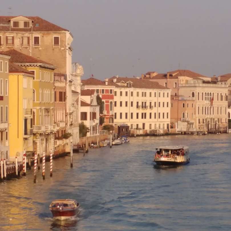 oameni călare pe barcă pe râu lângă clădiri în timpul zilei puzzle online