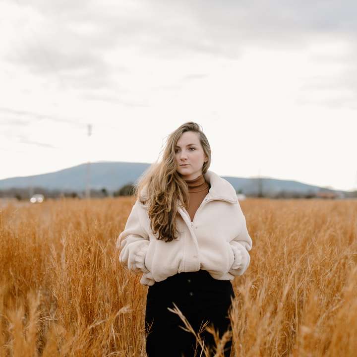 женщина в белой куртке стоит на поле коричневой травы раздвижная головоломка онлайн