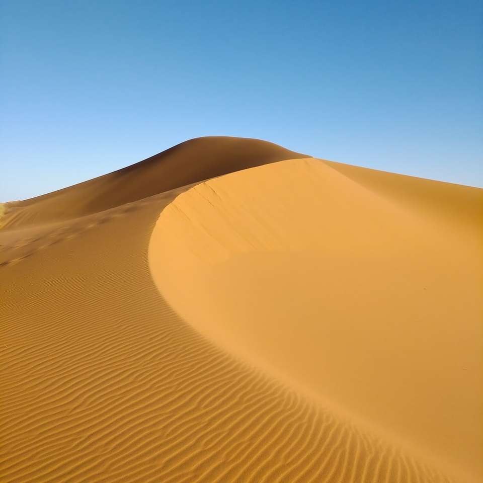 brun sand under blå himmel under dagtid glidande pussel online