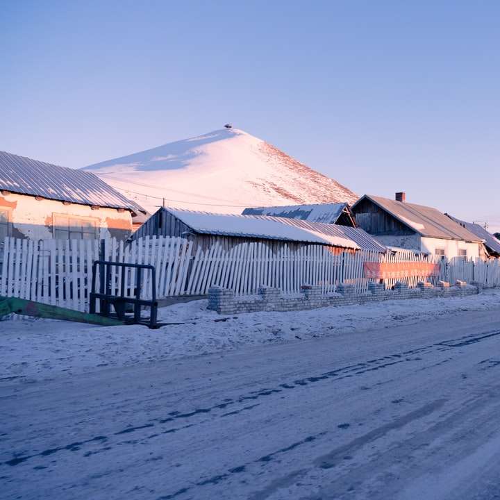 casas de madeira brancas e marrons perto de campo coberto de neve puzzle deslizante online