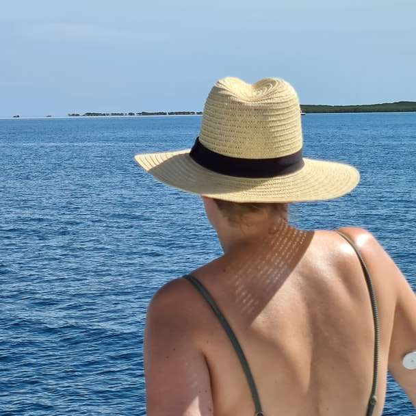 жінка в коричневому капелюсі сонця, що стоїть біля водойми онлайн пазл