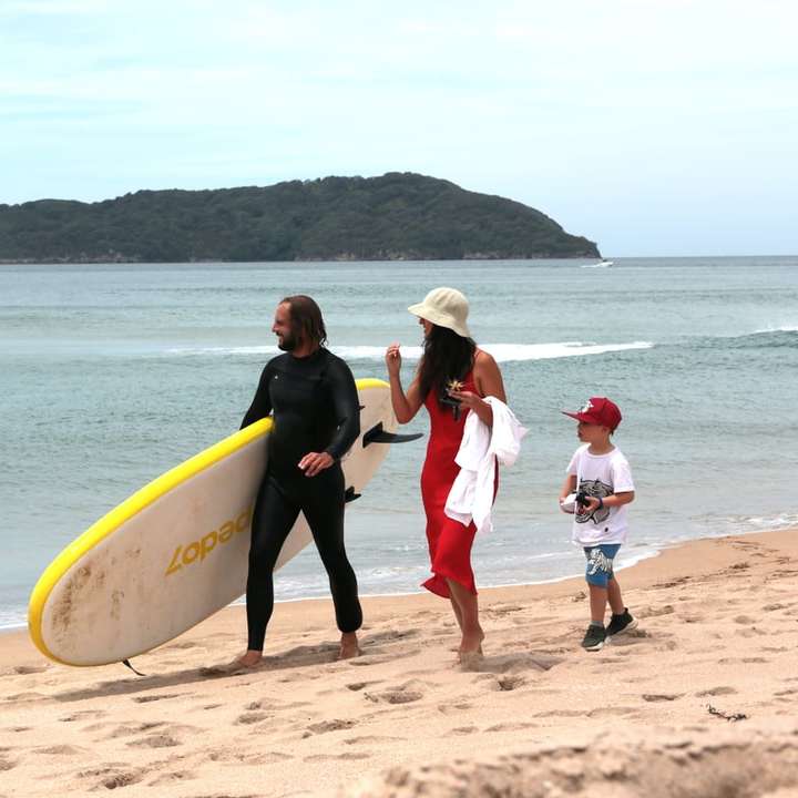mężczyzna i kobieta trzyma żółtą deskę surfingową spaceru na plaży puzzle online