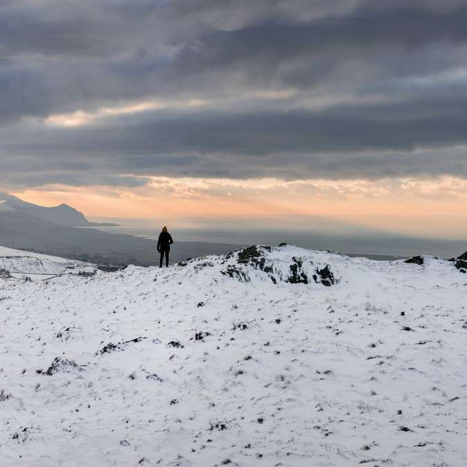 személy séta a hóval borított mezőben naplemente alatt csúszó puzzle online