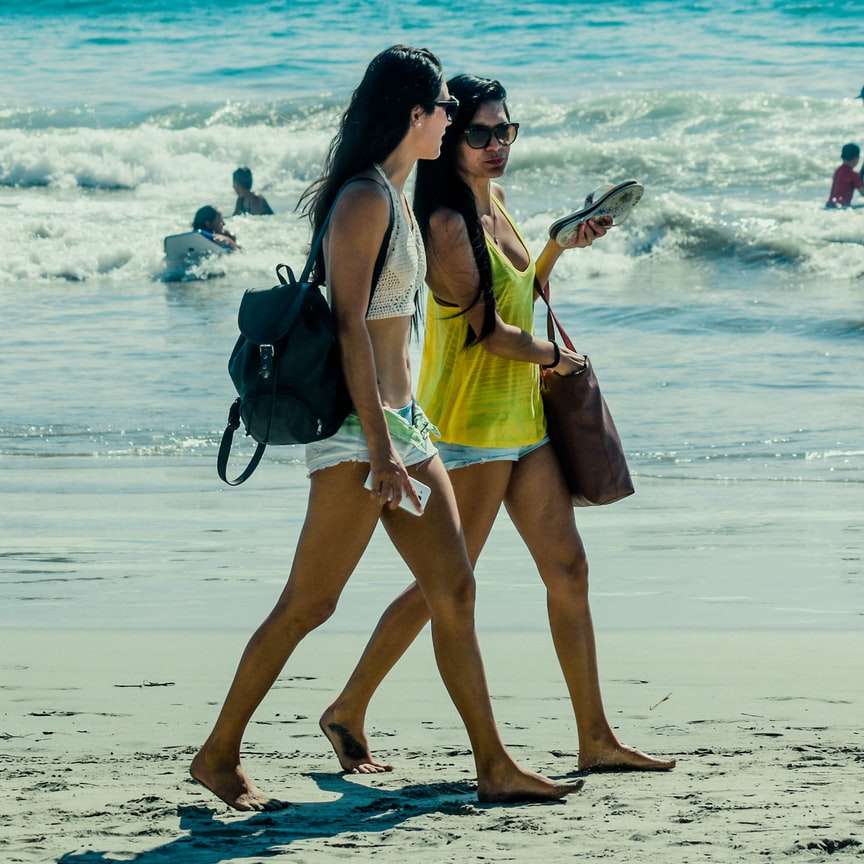 жена в жълт потник и бели шорти, стоящи на плажа плъзгащ се пъзел онлайн