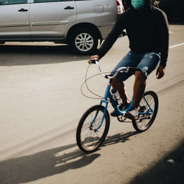 mężczyzna w czarnej kurtce, jazda na niebieskim rowerze w ciągu dnia puzzle online