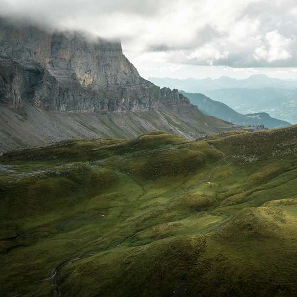grüne und braune Berge unter weißen Wolken während des Tages Schiebepuzzle online