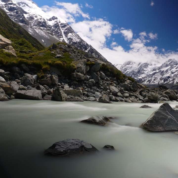 заснежени планини в близост до водоема през деня плъзгащ се пъзел онлайн