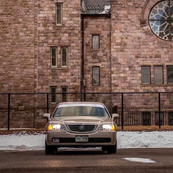Gelbes Auto, das tagsüber neben braunem Backsteingebäude geparkt wird Online-Puzzle