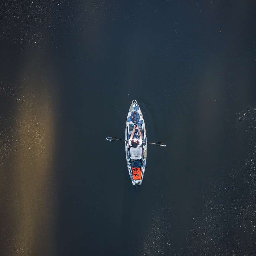 persoană călare pe barca albă și albastră pe apă în timpul zilei puzzle online