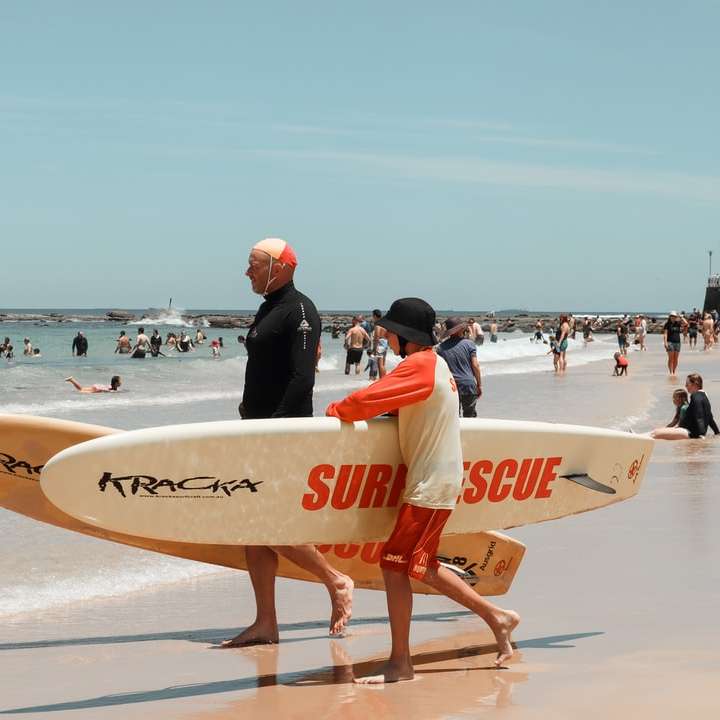 мъж в черен мокър костюм, държащ бяла дъска за сърф плъзгащ се пъзел онлайн