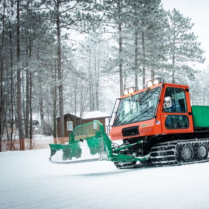 Tractor verde y naranja sobre suelo cubierto de nieve rompecabezas en línea