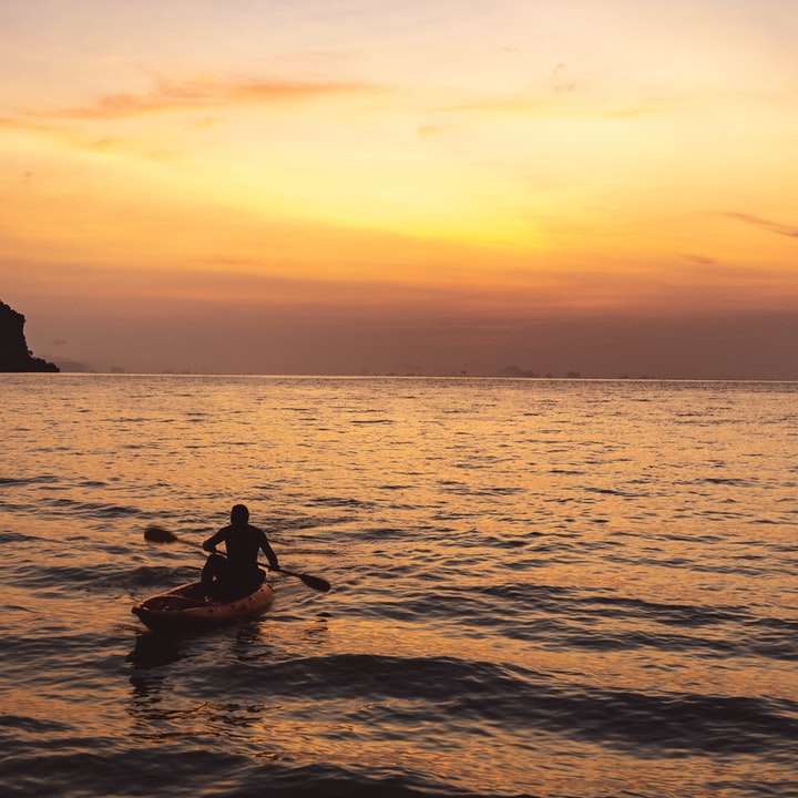 silhueta de homem andando de barco durante o pôr do sol puzzle deslizante online