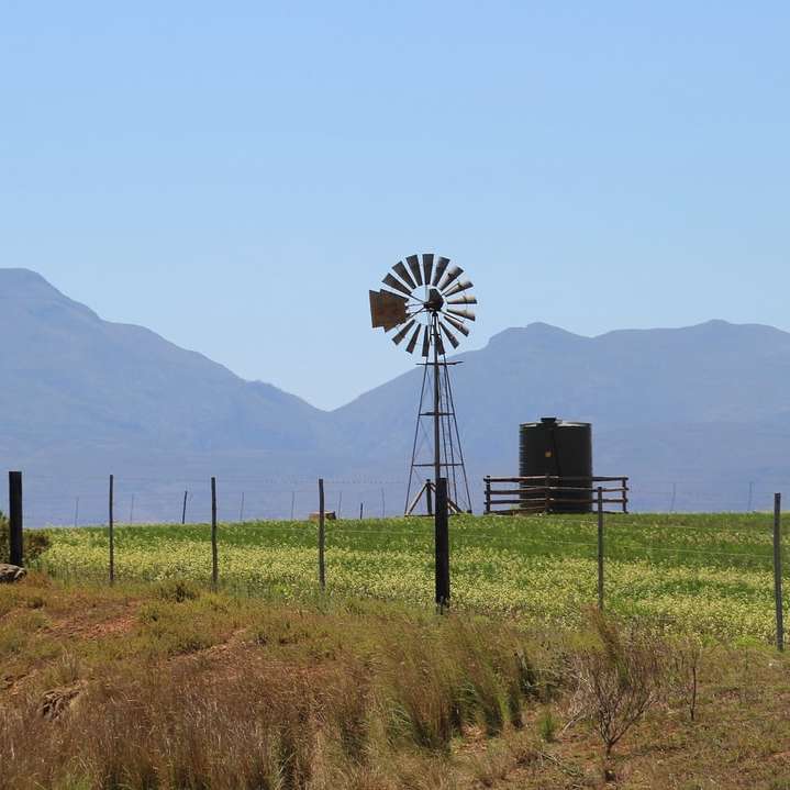 moinho de vento preto e branco em campo de grama verde durante o dia puzzle deslizante online