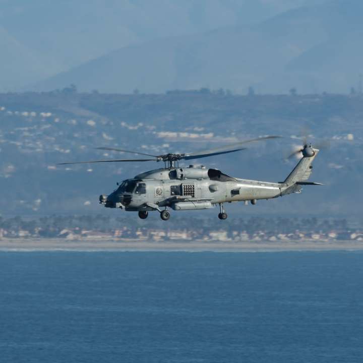 helicóptero branco e preto voando sobre o mar puzzle deslizante online