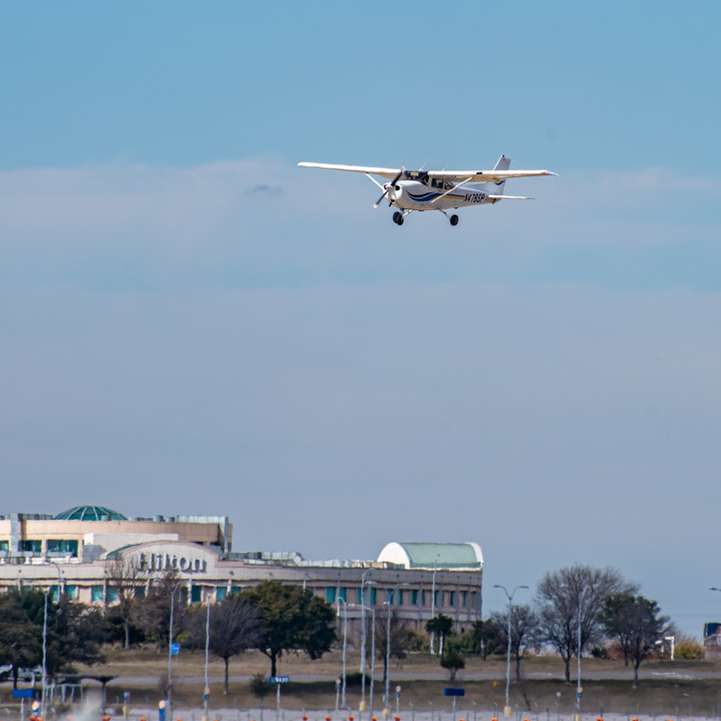 biało-czerwony samolot lecący nad miastem w ciągu dnia puzzle przesuwne online