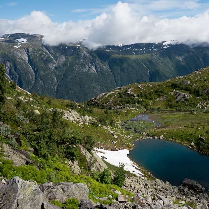 zielone i szare góry w pobliżu błękitnego jeziora w ciągu dnia puzzle przesuwne online