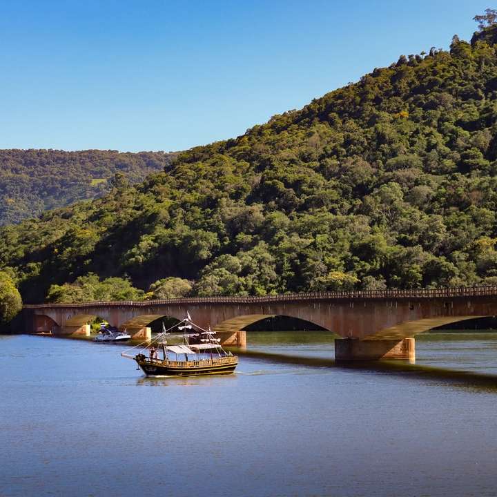 biała łódź na rzece w pobliżu mostu w ciągu dnia puzzle online