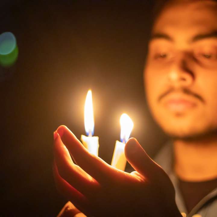 mężczyzna w szarej koszuli trzymający zapaloną świecę puzzle online