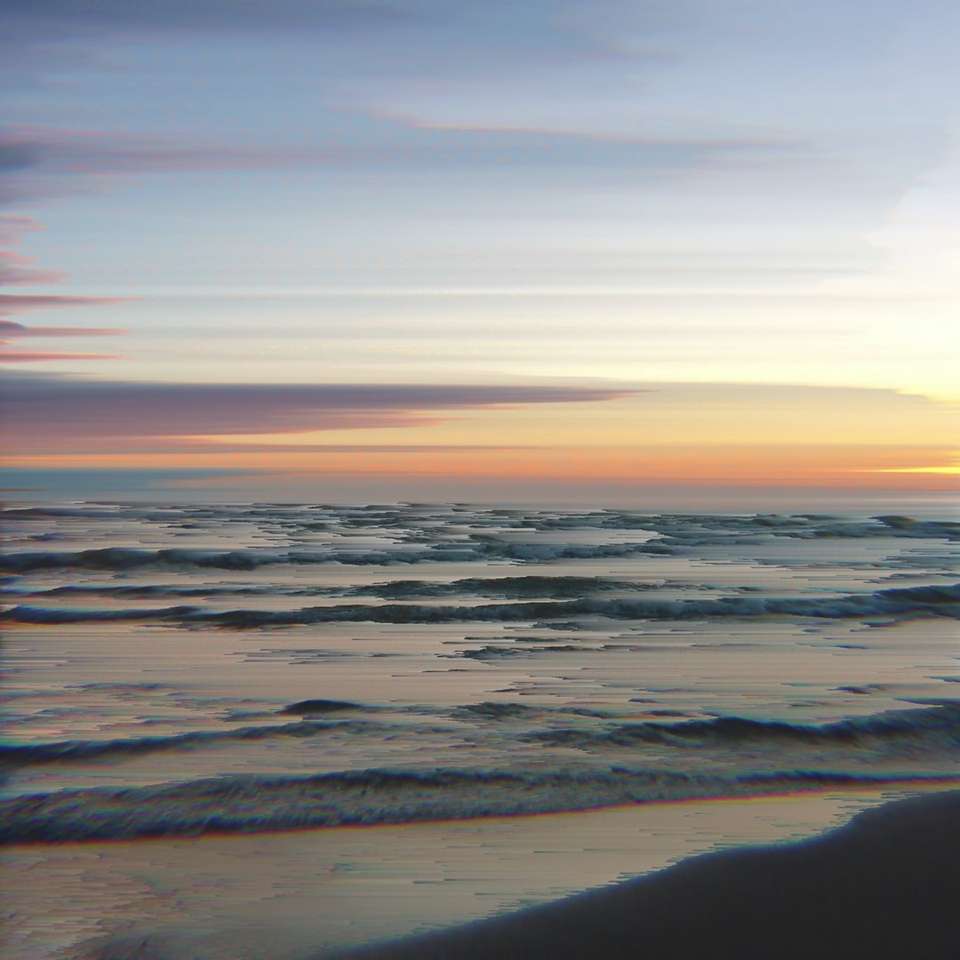 ondas do mar batendo na costa durante o pôr do sol puzzle deslizante online