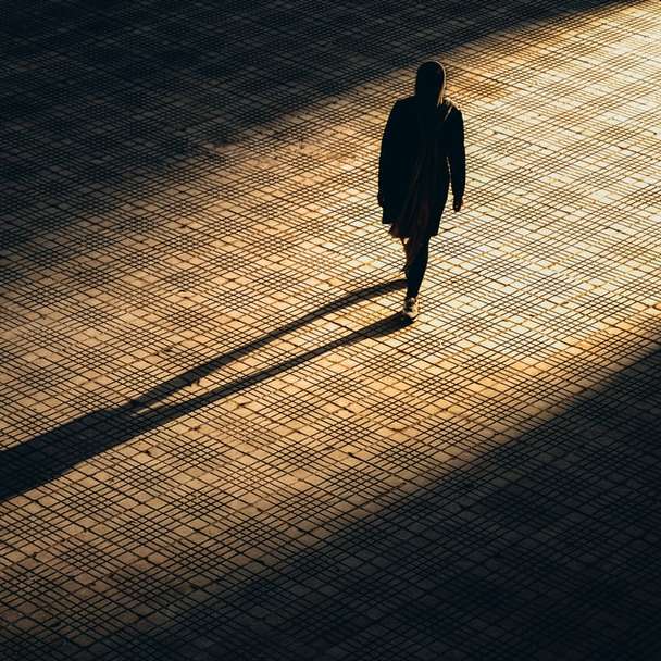 Hombre de chaqueta negra caminando sobre piso de ladrillo marrón rompecabezas en línea