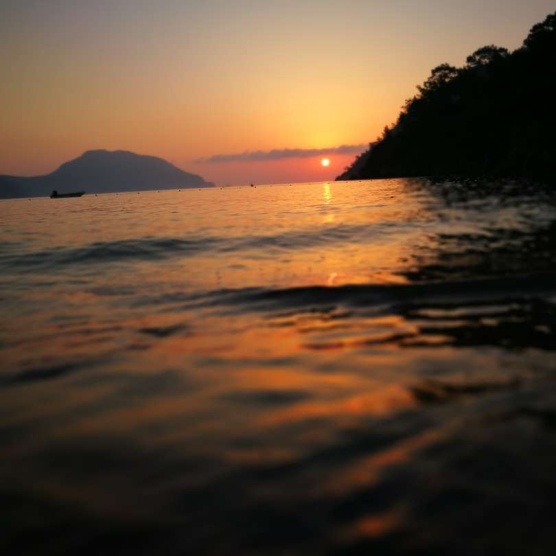 sagoma della montagna vicino al corpo d'acqua durante il tramonto puzzle scorrevole online