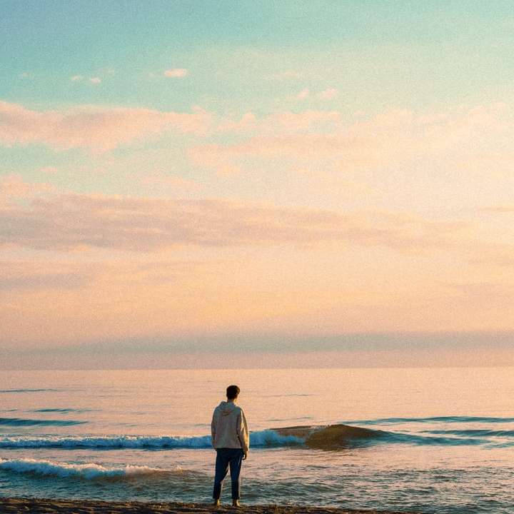 Hombre con camisa blanca de manga larga de pie en la orilla del mar puzzle deslizante online
