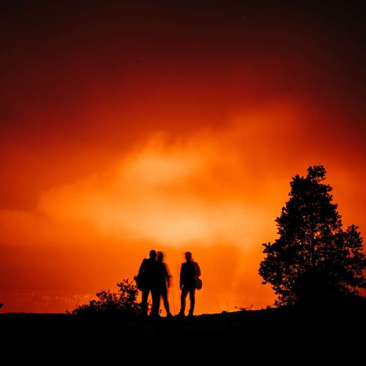 silhuett av 3 män som står på marken under solnedgången Pussel online