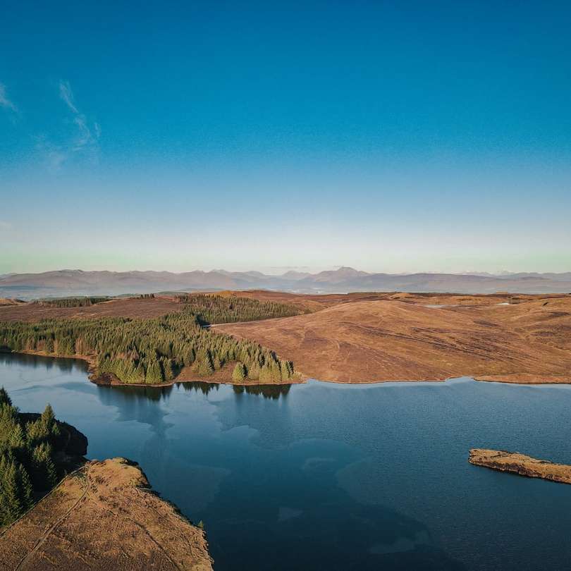 montagne marroni vicino al lago sotto il cielo blu durante il giorno puzzle online