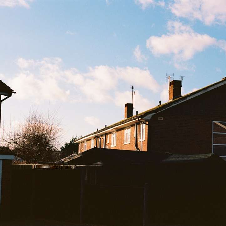 бело-коричневый деревянный дом возле голых деревьев под голубым небом онлайн-пазл