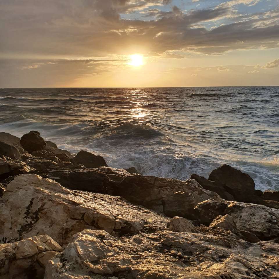 szürke sziklás parton naplemente alatt csúszó puzzle online