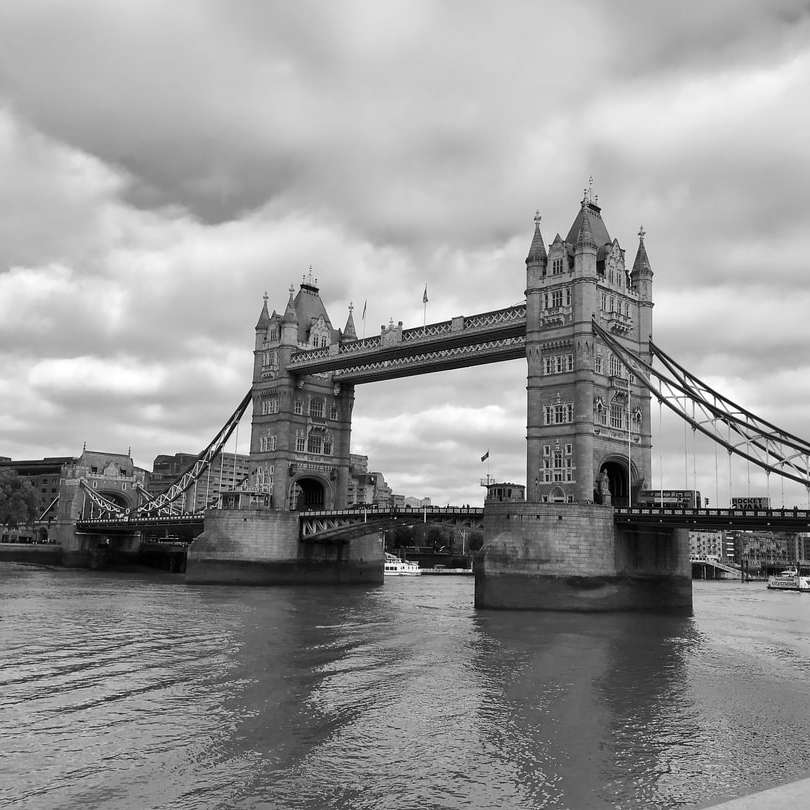 photo en niveaux de gris du pont sous un ciel nuageux puzzle en ligne