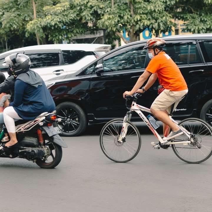 Mann im orangefarbenen T-Shirt, das auf weißem Fahrrad reitet Online-Puzzle