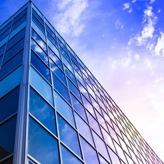 Edificio de gran altura con paredes de vidrio bajo un cielo azul puzzle deslizante online