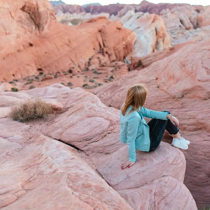 женщина в синей куртке сидит на коричневой скале онлайн-пазл