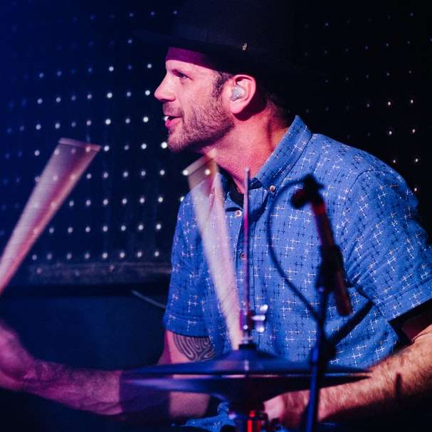 Hombre de camisa azul con botones tocando el tambor rompecabezas en línea
