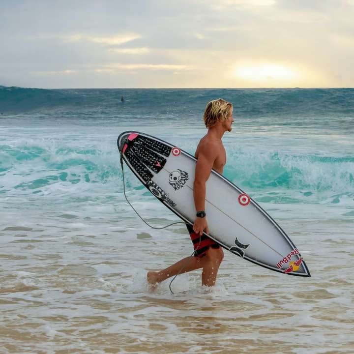 femme en bikini blanc et noir tenant une planche de surf blanche puzzle en ligne