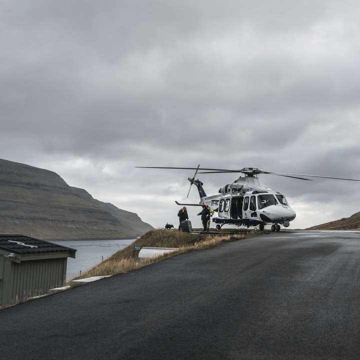 山の上を飛んでいる白と黒のヘリコプター スライディングパズル・オンライン