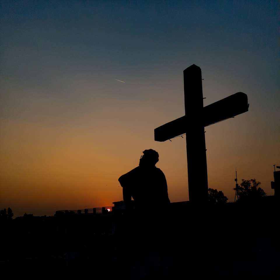silhouette d'homme debout près de croix pendant le coucher du soleil puzzle coulissant en ligne