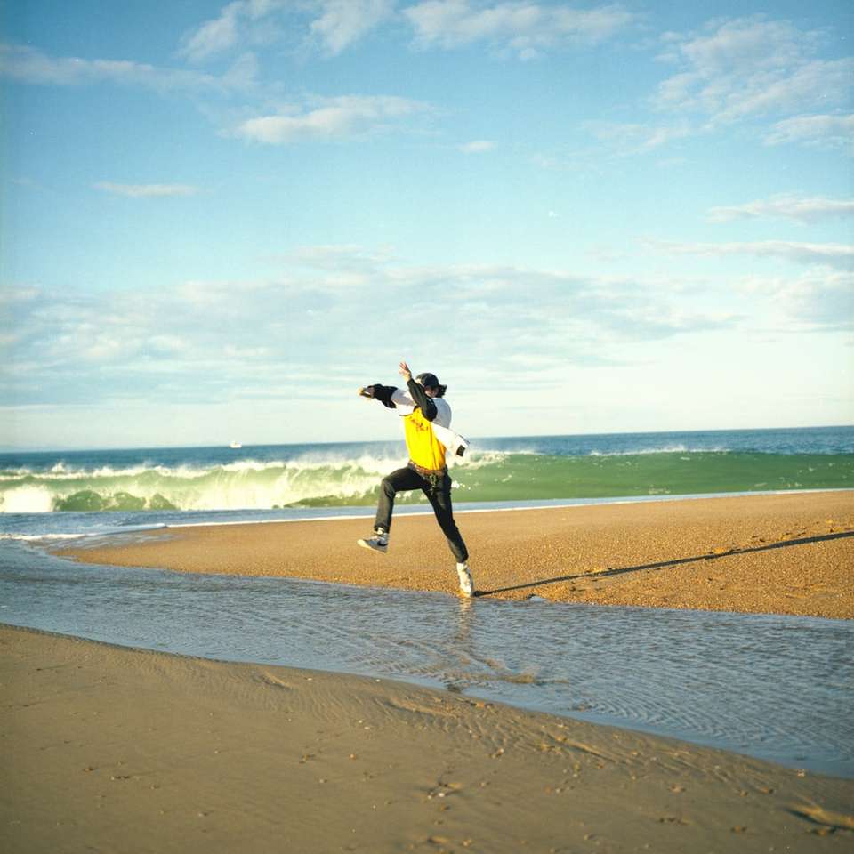 γυναίκα σε μαύρο σακάκι και κίτρινη φούστα στέκεται στην παραλία συρόμενο παζλ online