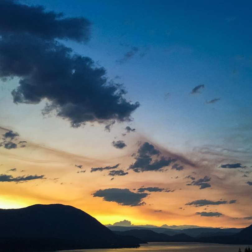 silhueta da montanha sob o céu azul durante o pôr do sol puzzle online