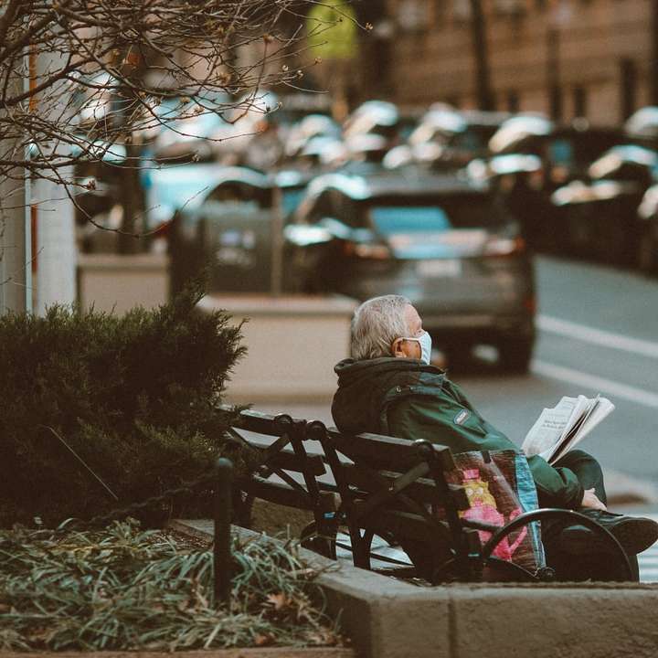 vrouw in zwarte jas zittend op een bankje in de straat online puzzel
