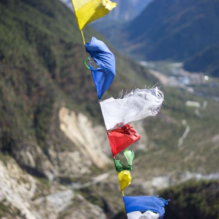 bandeira amarela, azul e vermelha na montanha rochosa durante o dia puzzle deslizante online