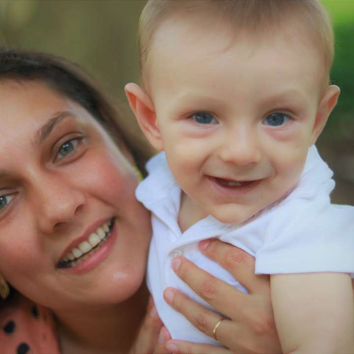 lächelnde Frau, die Baby im weißen Hemd hält Online-Puzzle
