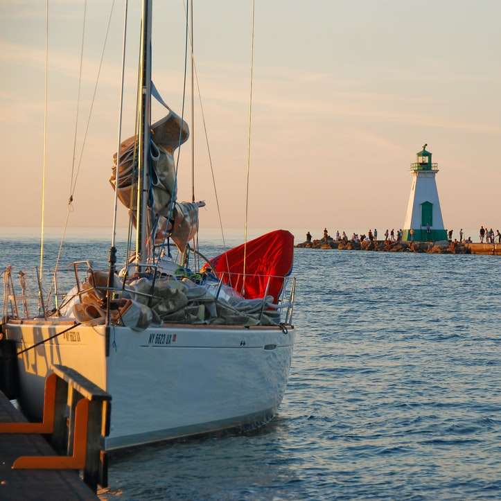 barca cu pânze albe și roșii pe mare în timpul zilei alunecare puzzle online