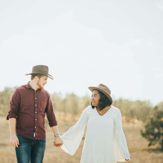 Mann und Frau, die Hände halten, während sie auf Feld gehen Schiebepuzzle online