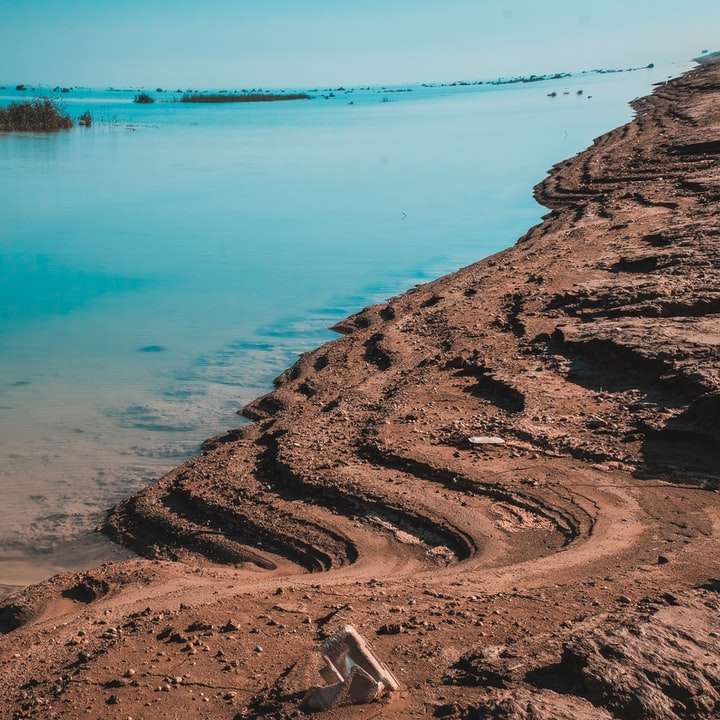 brązowy piasek w pobliżu zbiornika wodnego w ciągu dnia puzzle online