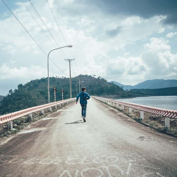 άντρας με μαύρο σακάκι και τζιν μπλε τζιν περπάτημα στη γέφυρα online παζλ