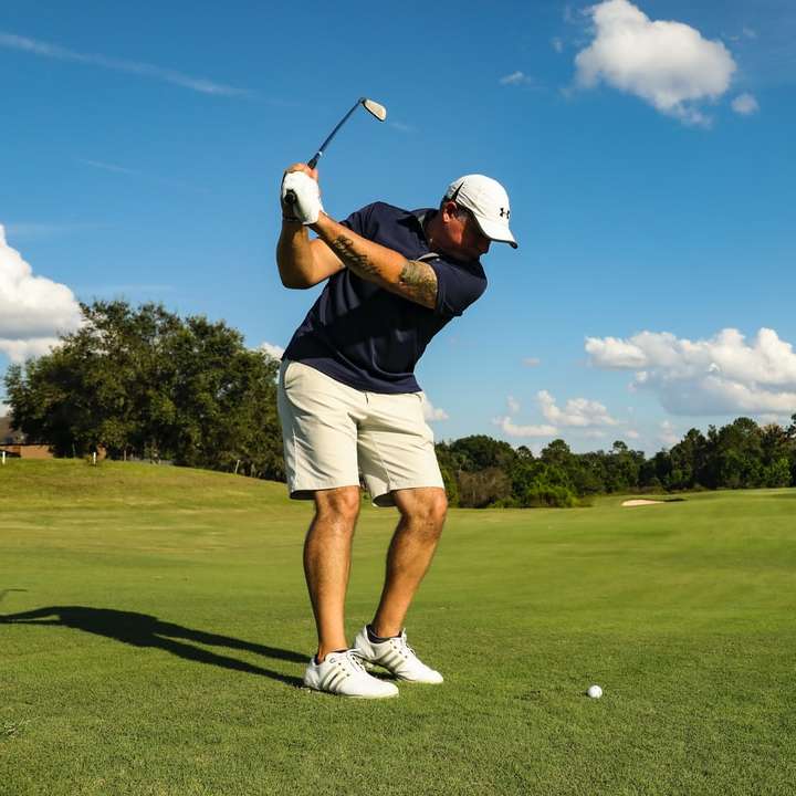 Hombre con camisa negra y pantalón blanco jugando al golf rompecabezas en línea